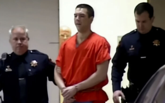 Scott Peterson, in a red jumpsuit, being escorted by officers, likely related to the Laci Peterson homicide. Scott Peterson, in a red jumpsuit, being escorted by officers, likely related to the Laci Peterson homicide.