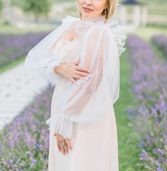 A smiling woman in a field of lavender, reflecting on infuriating MILs stories.
