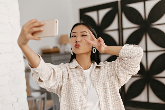 Influencer bestie poses for a selfie, showing peace sign and pouty lips, before ghosting a bride on her wedding day. Influencer bestie poses for a selfie, showing peace sign and pouty lips, before ghosting a bride on her wedding day.