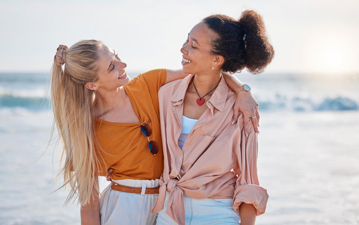 Influencer bestie and bride smiling together on a beach, highlighting their friendship before the wedding day ghosting. Influencer bestie and bride smiling together on a beach, highlighting their friendship before the wedding day ghosting.