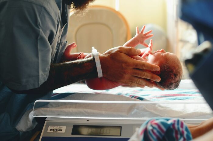 A medical professional gently holding a newborn baby, perhaps hinting at life's unsolved mysteries.