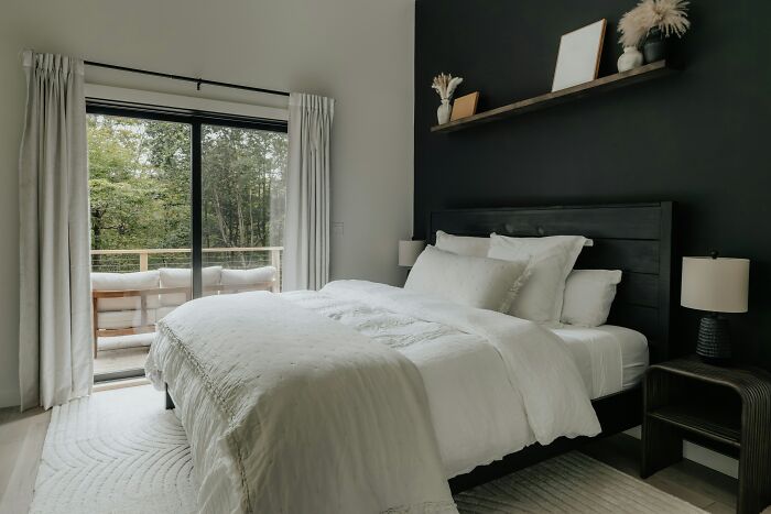 A modern bedroom with white bedding and balcony, a peaceful escape from MILs.