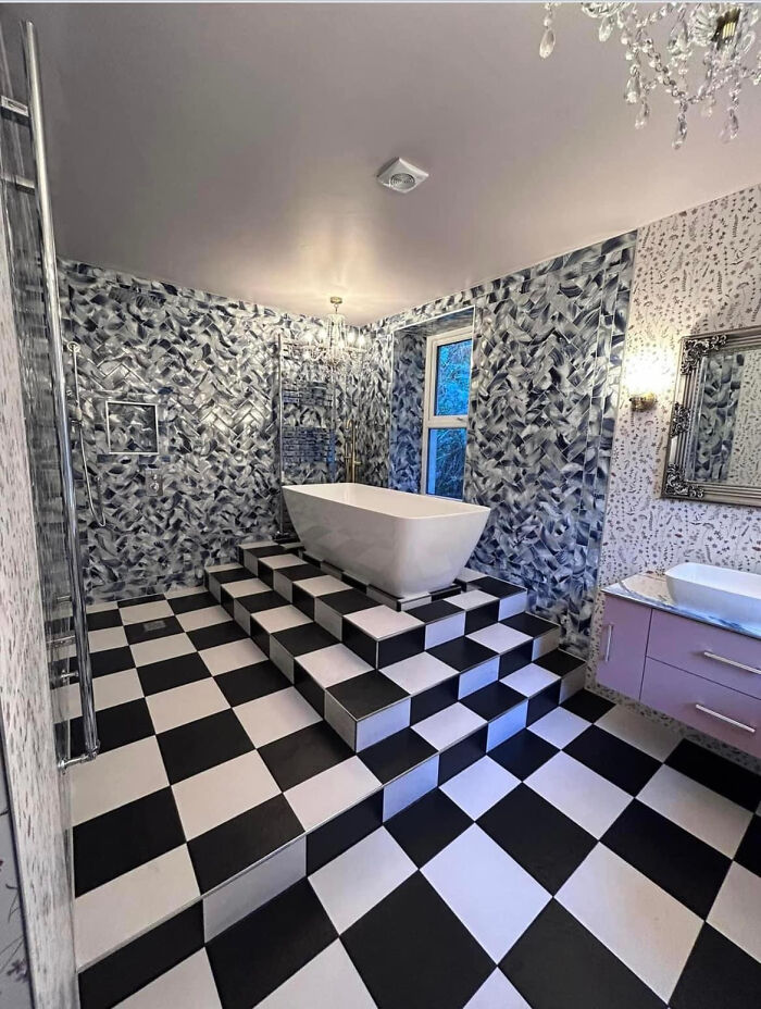 An eccentrically designed bathroom featuring a bathtub on a raised platform with black and white checkered steps.