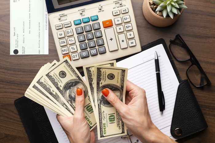 A person counting money, with a calculator and corporate documents on the desk, illustrating corporate practices.