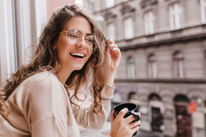 A smiling woman holding a cup, possibly involved in one of the unpopular industries that make millions.