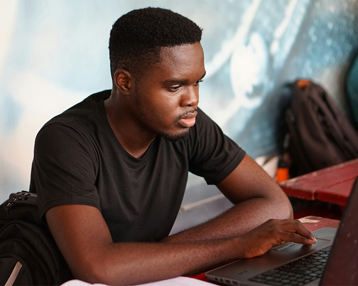 A college student uses a laptop, representing the prevalence of AI use among students on a final exam.
