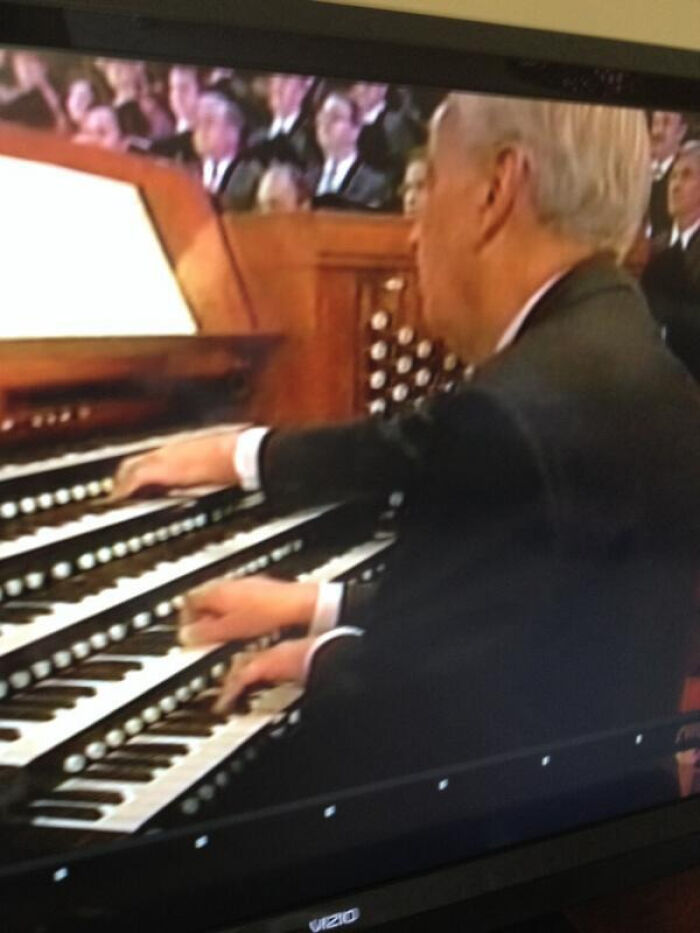 A man playing a large organ, a photo that may need to be looked twice at to fully understand the scene.