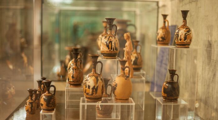 A display of ancient history tools, historic tools like intricately painted Greek vases and earthenware, showcased in a museum.