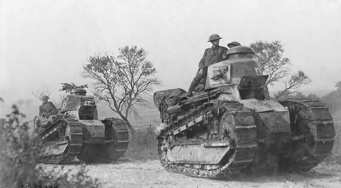 WWI recruit on a tank moving on the battlefield; a second tank is visible in the background, offering a glimpse into military history. WWI recruit on a tank moving on the battlefield; a second tank is visible in the background, offering a glimpse into military history.
