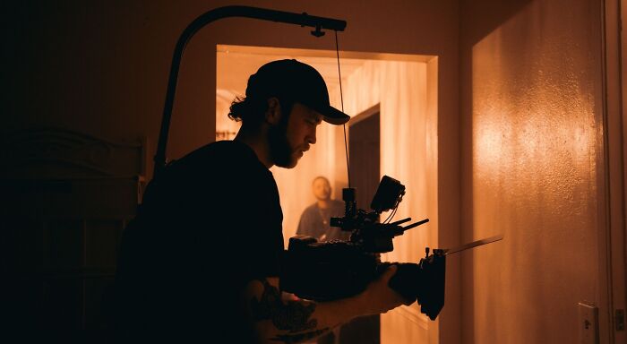 A film fan holding a camera filming an actor in a doorway, capturing BTS photos of movie production. A film fan holding a camera filming an actor in a doorway, capturing BTS photos of movie production.