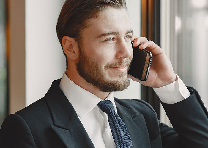 Smiling man in a suit talking on phone, depicting a successful job interview.