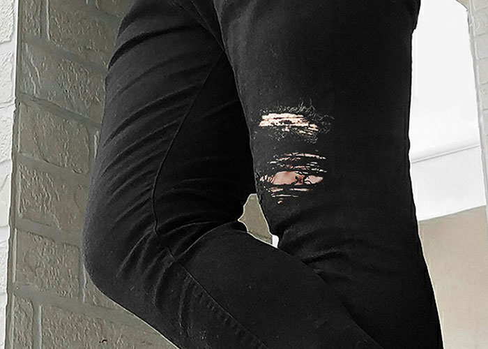 Close-up of ripped black jeans, symbolizing an unexpected situation during a job interview.