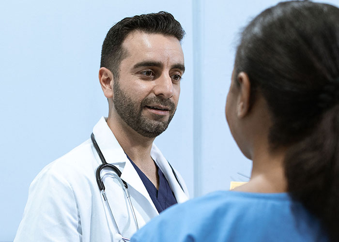 A male doctor speaking to a female patient, symbolizing job interview scenarios.