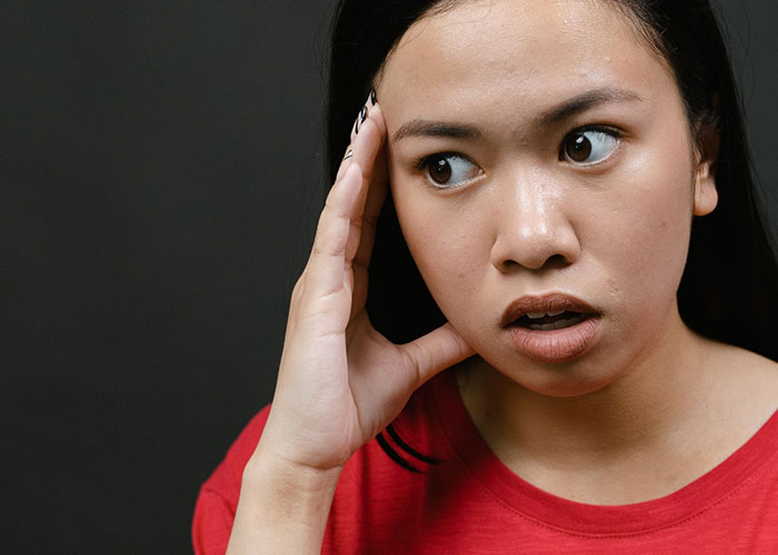 A young woman with a shocked expression, reacting to an unhinged job interview story.