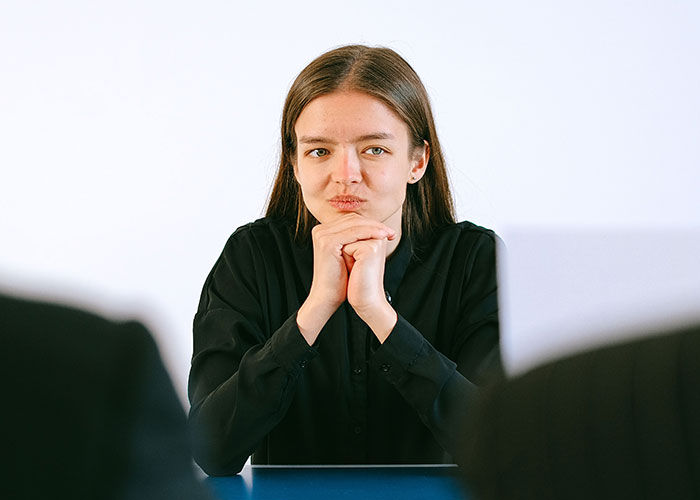 A woman looking intently during an interview, depicting the intensity of job interview stories.