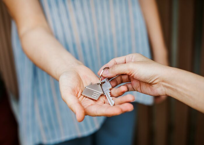 A hand gives house keys to another hand. This image relates to stories about a last will and testament.
