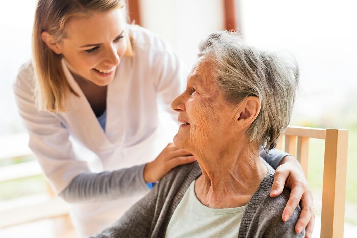 A young caregiver smiles at an older woman. This illustrates stories about a last will and testament.