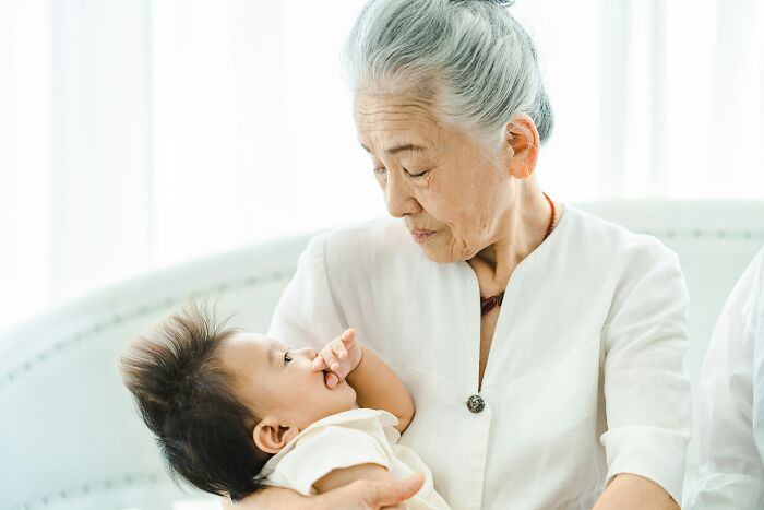 An elderly woman holding a baby, reflecting on the generations and the impact of a last will.