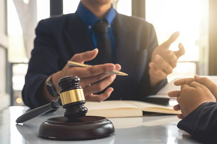 A gavel on a desk in front of a lawyer discussing last will stories with a client, emphasizing the legal aspect.