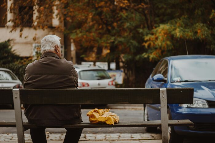 An older man sits alone on a park bench. This evokes thoughts about a last will and testament.