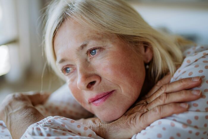 A thoughtful elderly woman, contemplating her last will and testament and burial requests.