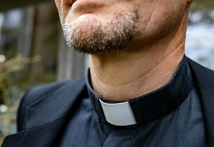 A close-up of a priest with a clerical collar, representing the serious last will stories.