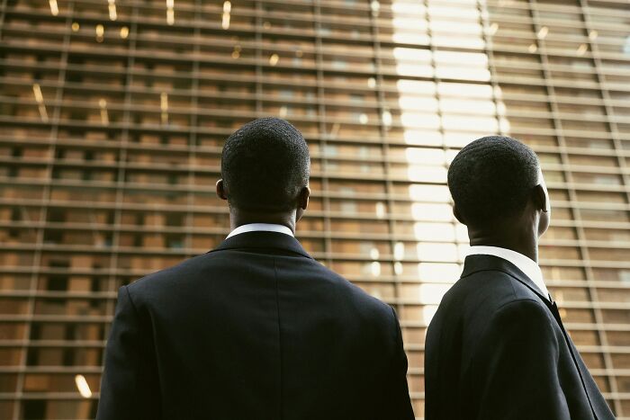 Two men in suits looking at a modern building, symbolizing the serious and sometimes funny aspects of last will stories.