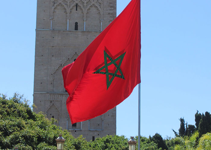 The Moroccan flag waving in front of the Hassan Tower. Discover facts about America and other nations.
