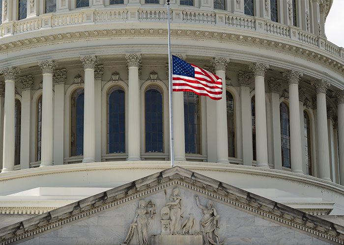 American flag at half-mast over the U.S. Capitol building, symbolizing important facts about America.