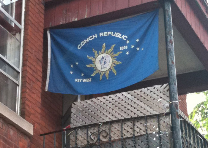 A Conch Republic flag hanging from a balcony, showcasing unique America facts.