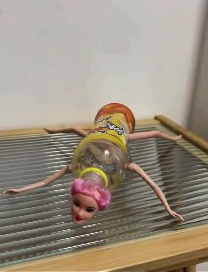 A creepy and confusing image of a Barbie doll's head and limbs attached to a plastic bottle, resembling a spider-like creature.