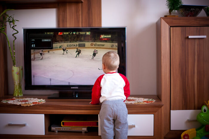 A young child watching ice hockey on TV, a common childhood experience.