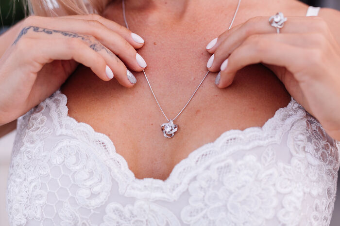 A woman adjusting a necklace, representing cherished childhood experiences or milestones.