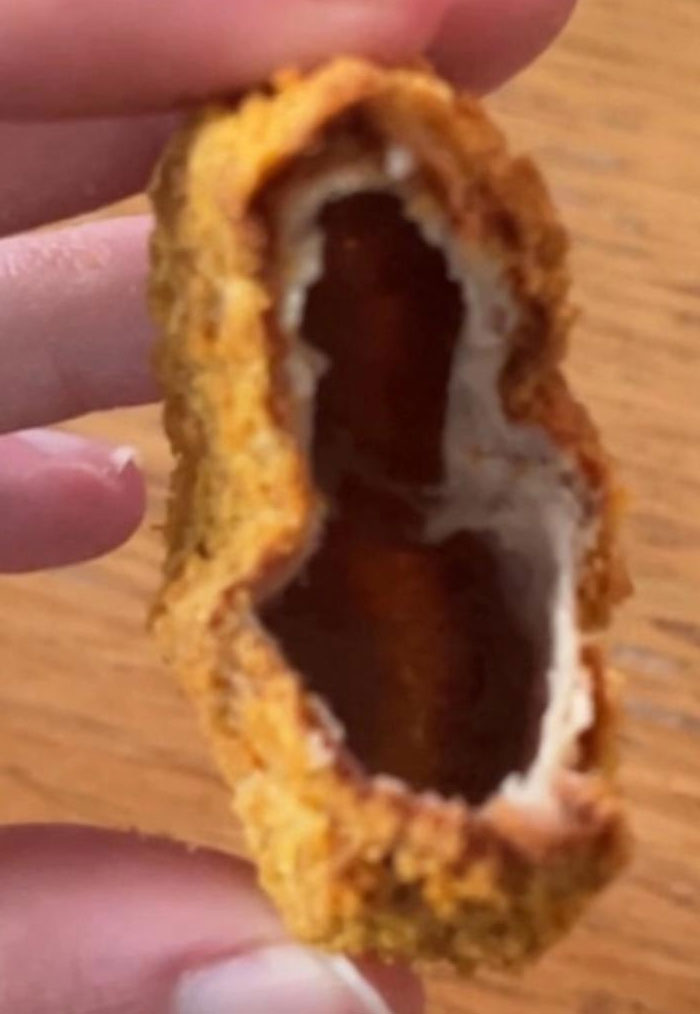 A close-up of a hollow, fried chicken nugget, revealing an empty interior, a perplexing camera roll photo.