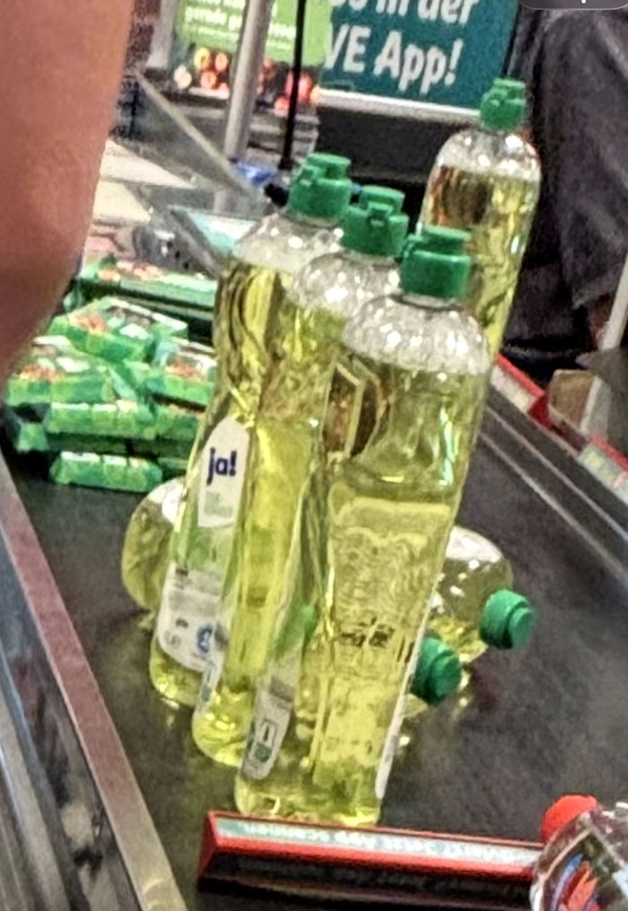 Multiple bottles of yellow dish soap, Ja! brand, lined up on a checkout conveyor belt, an odd camera roll photo.