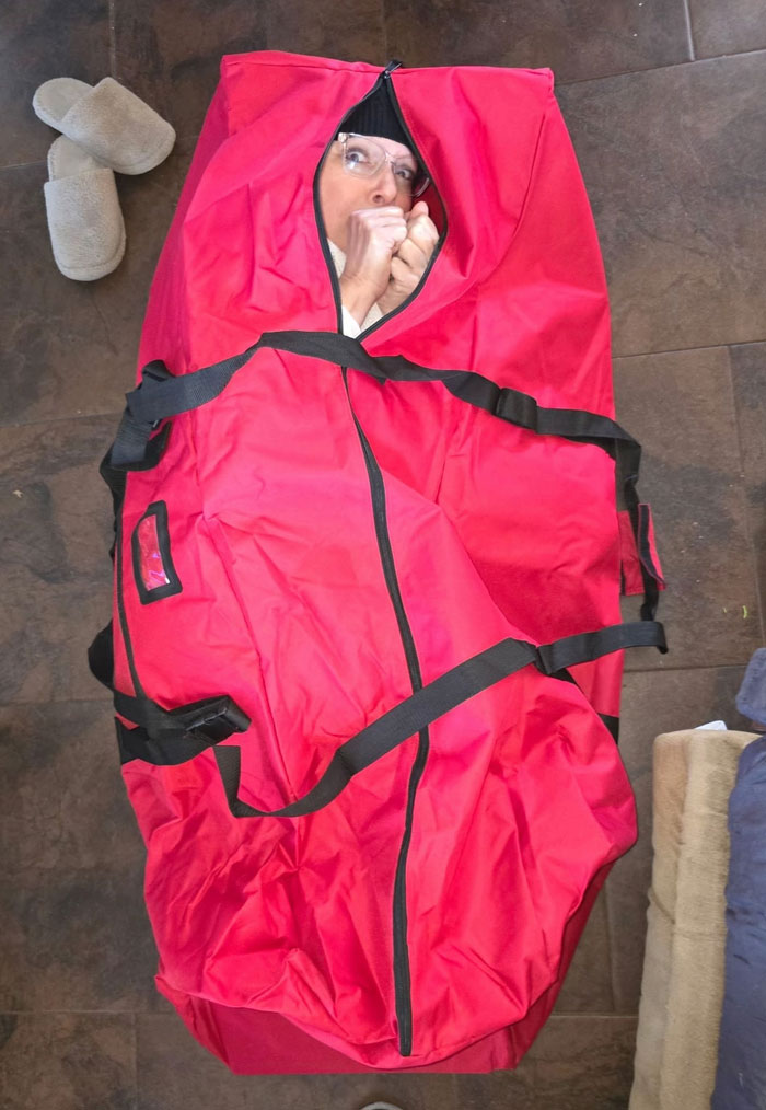 A person peeking out of a red bag, making a funny face, one of the camera roll photos that need no explanation.