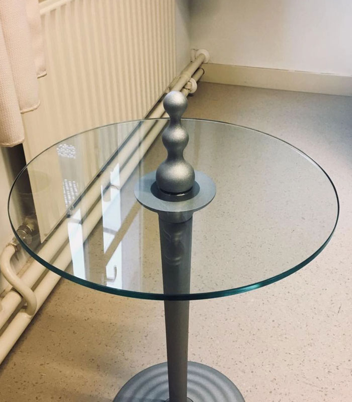 A modern glass-top table with a unique silver base, a striking object from a camera roll photo.