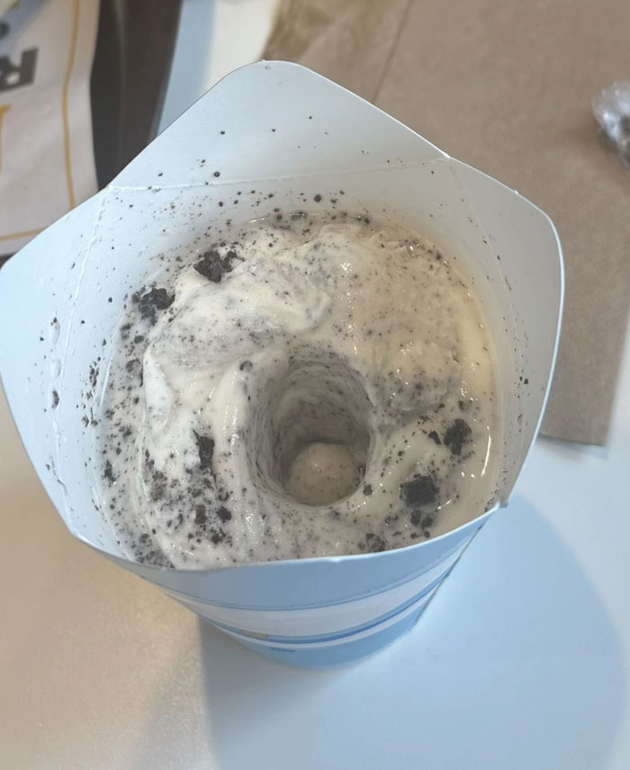 A camera roll photo showing a vanilla ice cream cup with a swirl of cookie crumbs and a central hole.