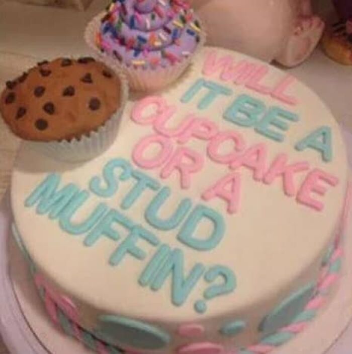 A round gender reveal cake asking Will it be a Cupcake or a Stud Muffin?, with a cupcake and muffin on top.