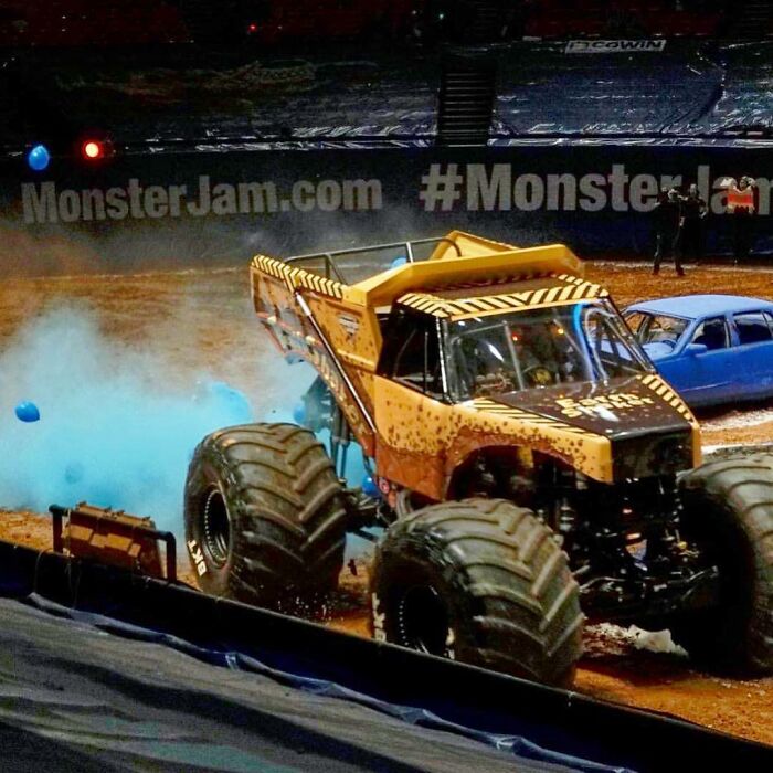 A Monster Jam truck releasing blue smoke, part of a unique gender reveal moment at a show.