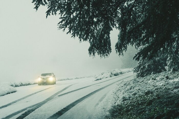A car driving on a snow-covered road under dark, misty conditions, illustrating a moment of instant justice.