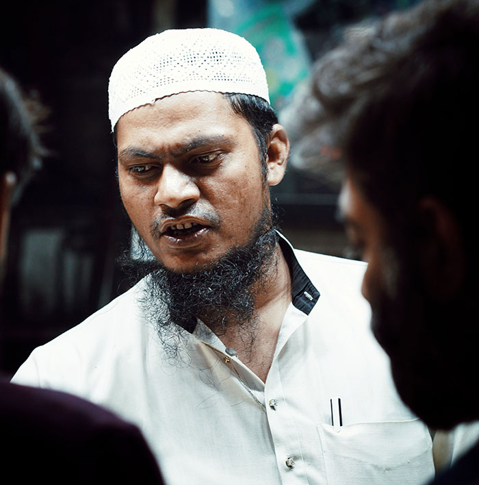 A man with a beard and a white cap engaging in conversation, depicting communication challenges in intercultural relationships.