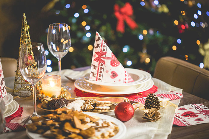 A festive table set for dinner with wine glasses, plates, and desserts, illustrating intercultural relationships.