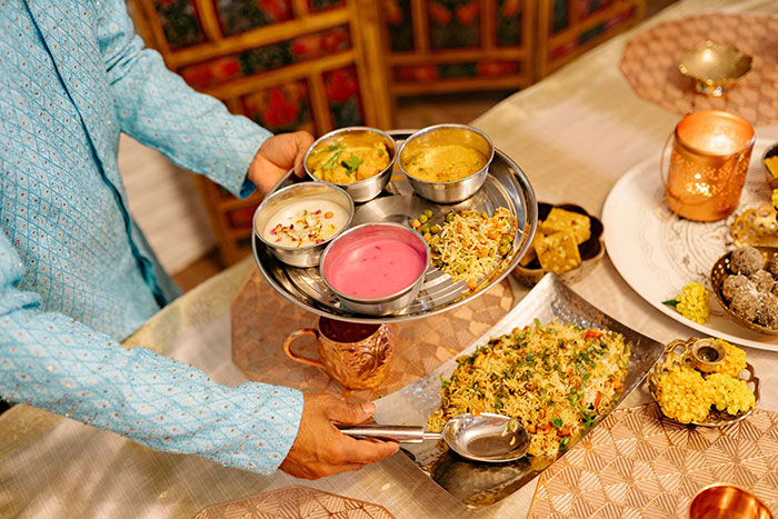 Hands serving a traditional meal on a platter, showcasing food customs that impact intercultural relationships.