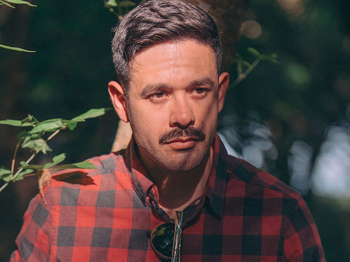 A man with a mustache in a plaid shirt, perhaps reflecting on intercultural relationships and culture shocks.