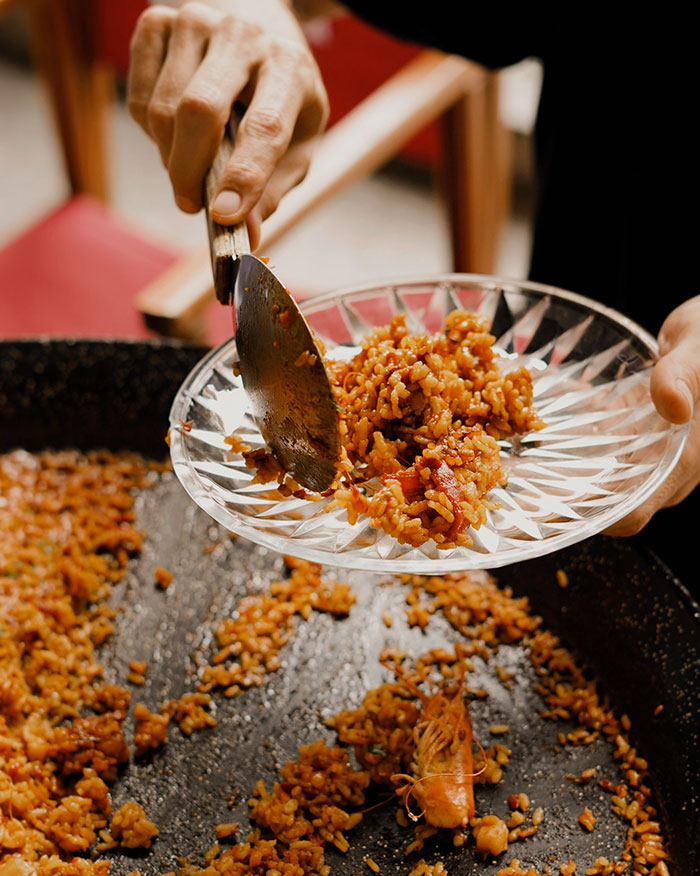 Someone serving a plate of paella, symbolizing an experience with culture shocks or intercultural relationships.