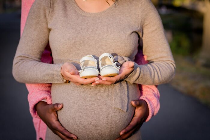 Future travelers holding baby shoes on a pregnant belly, symbolizing new beginnings and cultural experiences.