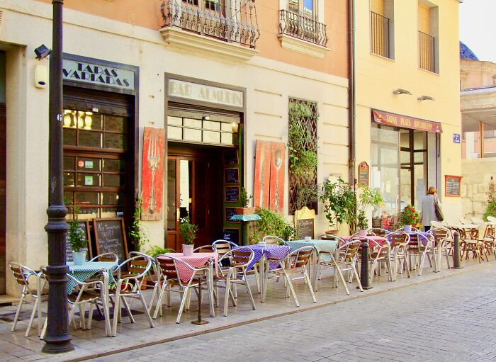 Travelers experiencing culture shock at a cafe with outdoor seating in a foreign city.