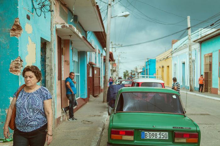 Travelers experiencing culture shock in a vibrant foreign city street with colorful buildings and parked cars.