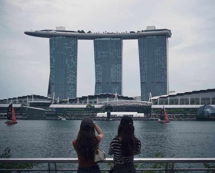Travelers observing the iconic Marina Bay Sands hotel and waterfront, potentially experiencing culture shock.